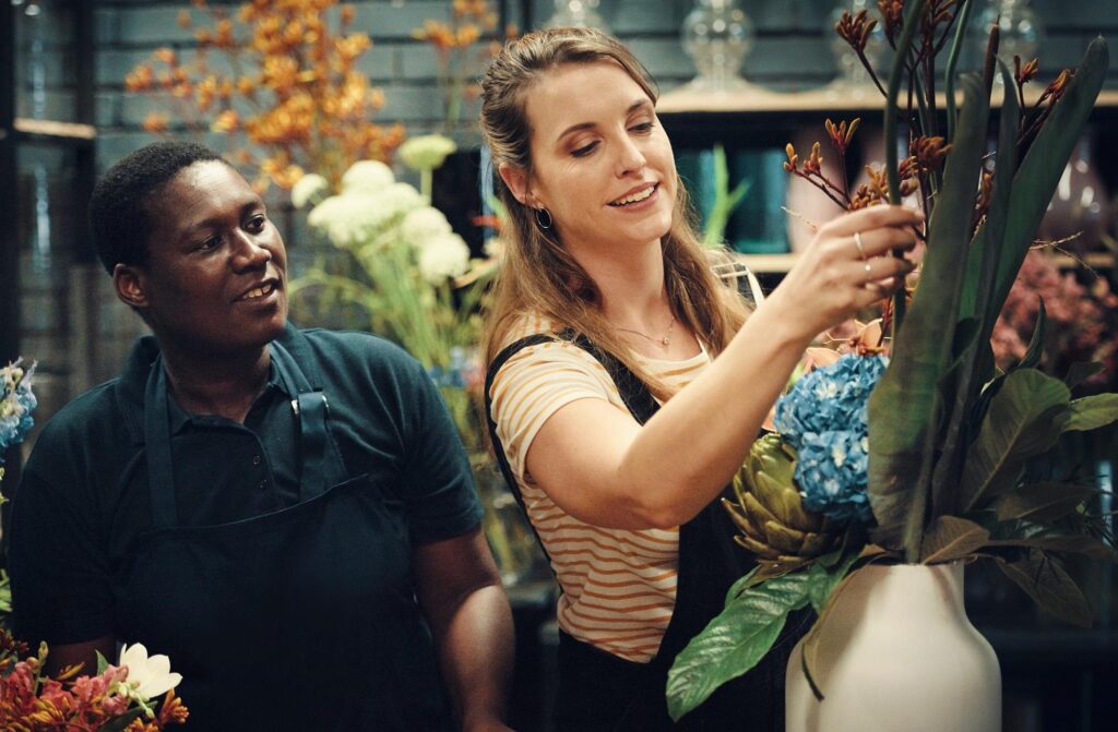 Two women florists arranging flowers in a shop - We do events